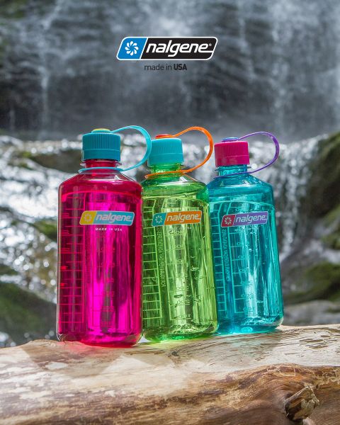 Tre colorate borracce Nalgene (rosa, verde e blu) sono posizionate su un tronco d'albero di fronte a una cascata. Ogni borraccia ha un tappo a vite e un anello per il trasporto. Sopra spicca il logo Nalgene con la scritta "Made in USA".