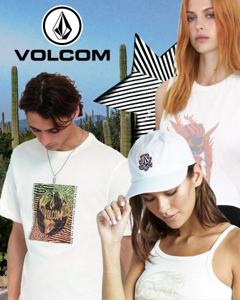 Tre model in abbigliamento Volcom posano davanti a un paesaggio desertico con cactus. Il modello maschile indossa una t-shirt bianca con grafica, la modella con i capelli arancioni un top bianco e l'altra modella un cappellino e una canotta bianca. In alto, logo Volcom.