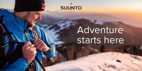 Una persona con una giacca blu e un cappello nero controlla il dispositivo al polso mentre si trova su una montagna innevata al tramonto. Il cielo è arancione e sullo sfondo si vedono le montagne. Il testo dice: "L'avventura inizia qui".