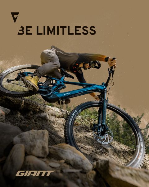 Un ciclista sta percorrendo un terreno roccioso con una mountain bike blu. Le parole "Be Limitless" e "Giant" sono visibili nell'immagine. Il ciclista indossa un casco e abbigliamento da ciclismo, sottolineando l'avventura e la libertà sul sentiero.