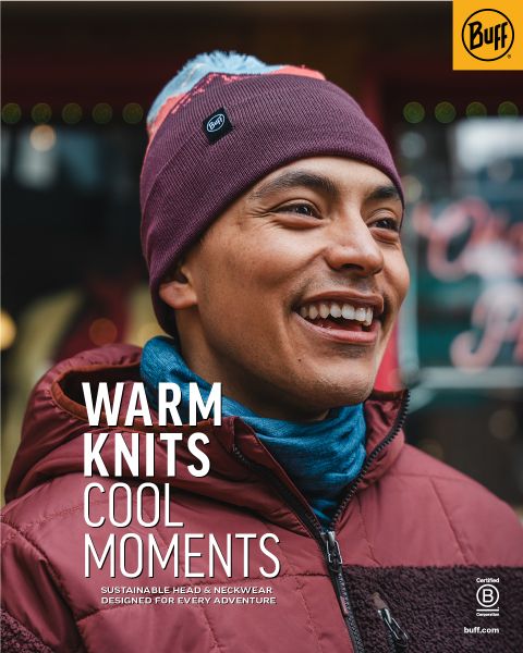 Una persona sorridente con un berretto di maglia color castagna e una giacca color vinaccia è in piedi all'aperto. Il testo sull'immagine recita: "Maglieria calda, momenti cool. Copricapo e scaldacollo sostenibili per ogni avventura." Logo Buff visibile.