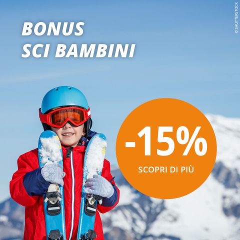 Un bambino sorridente in abbigliamento da sci rosso e con casco tiene in mano gli sci tra le montagne innevate. Il testo recita "BONUS SCI BAMBINI" e un grande cerchio arancione mostra "-15% SCOPRI DI PIÙ." Sullo sfondo si vedono cielo azzurro e cime montuose.