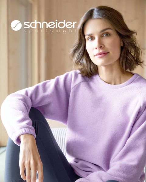 Una persona con capelli alle spalle, giacca casual e maglietta è in piedi davanti a uno sfondo neutro. Nella parte superiore dell'immagine si legge la scritta "Schneider Sportswear".