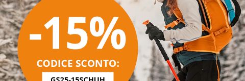 Una donna sorridente con uno zaino sta sciando in salita in un bosco innevato. Un cerchio arancione indica "-15% CODICE SCONTO: GS25-15SCHUH" per scarponi da sci e da montagna. Il testo in alto recita "BONUS SCARPONI DA SCI E ALPINISMO".