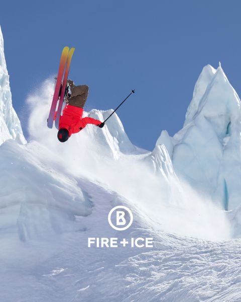 Due persone in abbigliamento invernale sciano su una montagna attraverso la neve. Indossano zaini e usano bastoncini per supporto. Sullo sfondo si vede un paesaggio nebbioso e vasto. L'immagine contiene un logo "Fire + Ice" nell'angolo in alto a sinistra.
