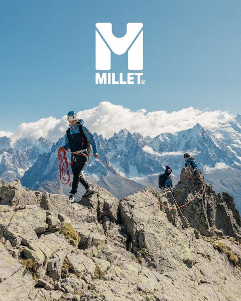 Tre escursionisti completamente equipaggiati camminano attraverso un paesaggio montano con cime innevate. In basso si vede una donna con una giacca che si sistema il colletto. Sullo sfondo si vedono le montagne. In basso a destra si vede il logo "Millet".