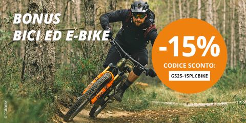 Un uomo con casco e occhiali da sole guida una mountain bike elettrica attraverso un bosco. Un grande cerchio arancione mostra "-15% CODICE SCONTO: GS25-15PLCBIKE". Il testo sopra recita: "BONUS BICI/E-BIKE".