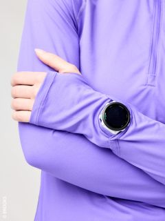 Una persona con una camicia a maniche lunghe viola incrocia le braccia e indossa uno smartwatch nero rotondo sopra la manica.
