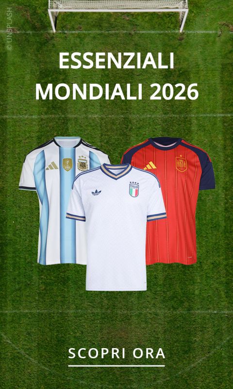 Tre maglie da calcio (Argentina, Italia, Spagna) sono visibili su un campo in erba, sopra il testo "ESSENZIALI MONDIALI 2026" e sotto "SCOPRI ORA".