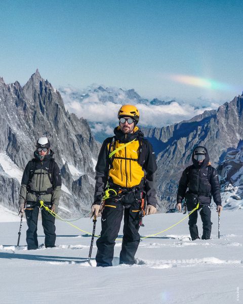 Due immagini su sfondo roccioso. A sinistra: donna in abbigliamento da trekking viola con casco. A destra: persona in abbigliamento verde-blu con zaino giallo, attrezzatura da arrampicata e corda arrotolata. Testo: "TIPO OUTDOOR ALPINISTA".