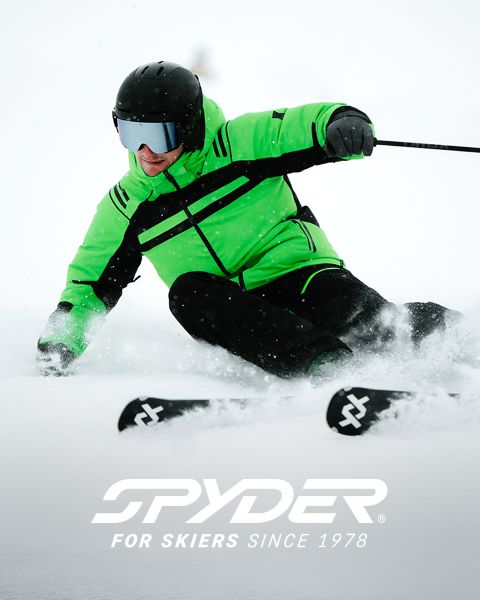 Uno sciatore in tenuta nera e gialla scende un pendio innevato, con un paesaggio innevato sullo sfondo. In alto c'è il testo: "SPYDER PER SCIATORI DAL 1978". Nell'angolo in basso a destra c'è un piccolo logo bianco a forma di ragno.